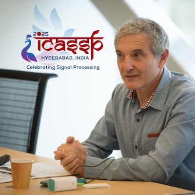 UC San Diego music professor Shlomo Dubnov sitting at a conference table, speaking to people behind the camera. To his right is the logo for the International Conference on Acoustics, Speech, and Signal Processing.